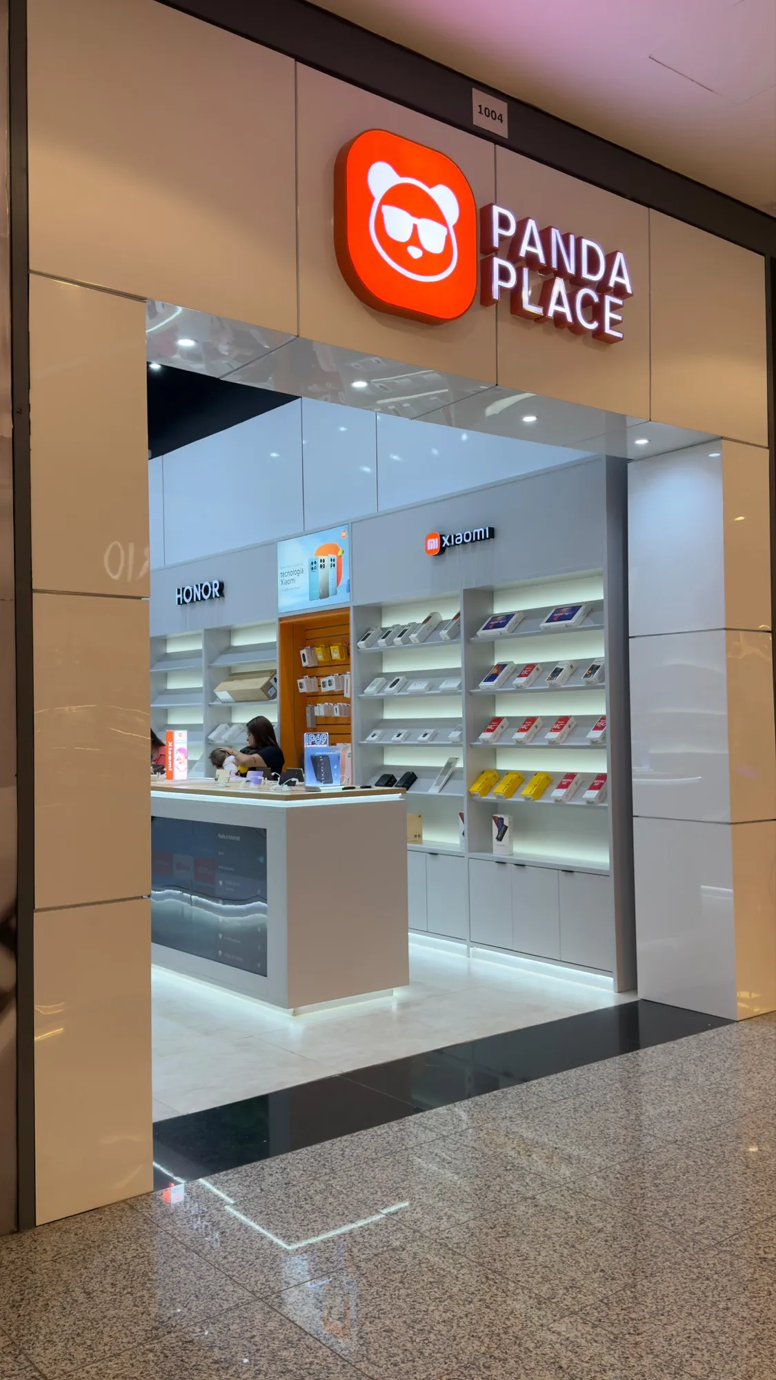 Fachada de uma loja Panda Place em shopping, com o símbolo da marca sobre a entrada