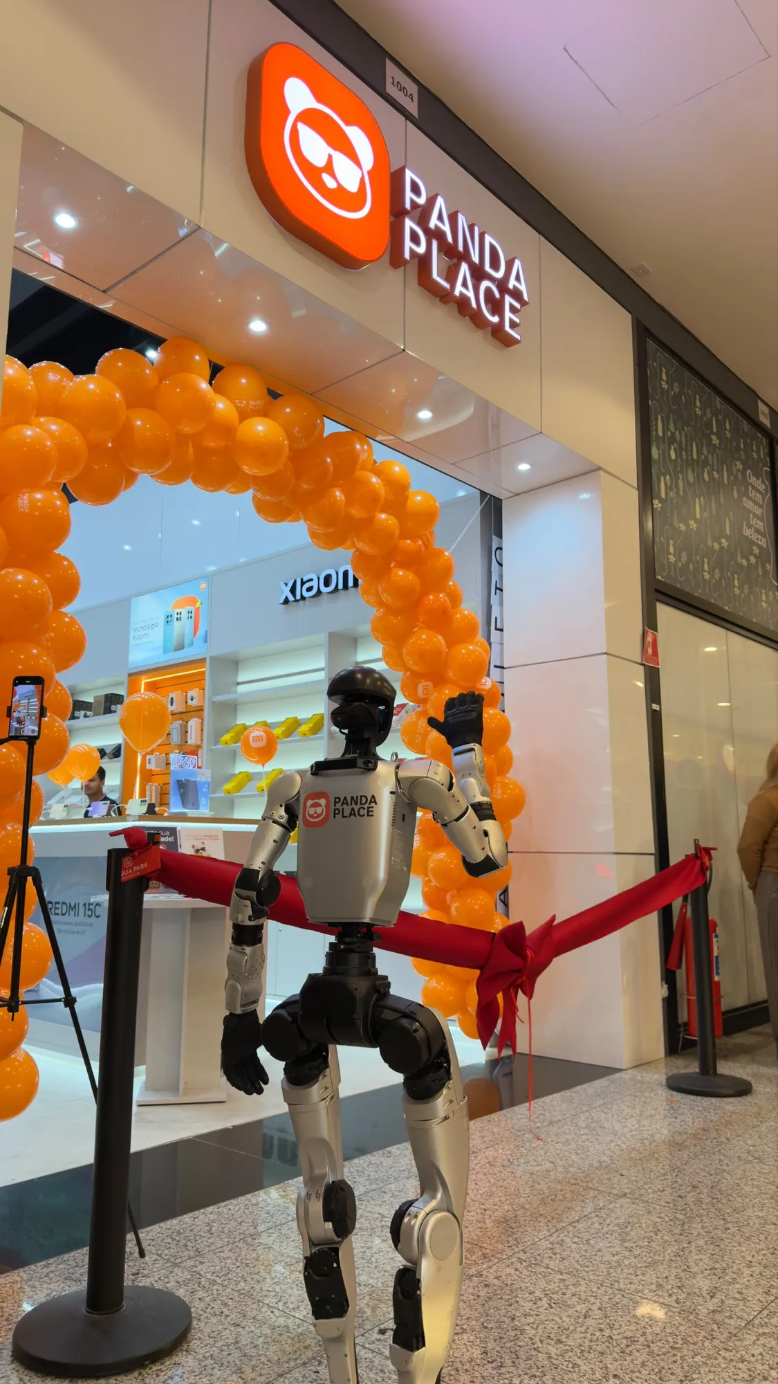 Entrada de uma loja Panda Place no dia da inauguração, com arco de balões laranja
